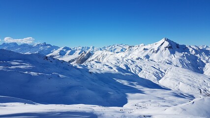 Sunny view over the peaks of white mountains of the French Alps from the ski area Les Trois Valless with clear blue sky