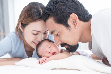 Obraz na płótnie Canvas smiling mother and father holding their newborn baby at home..portrait of happy family at home, young parents holding on hands little sweet newborn baby, love and happiness concept.