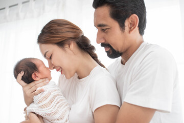 Fototapeta premium smiling mother and father holding their newborn baby at home..portrait of happy family at home, young parents holding on hands little sweet newborn baby, love and happiness concept.