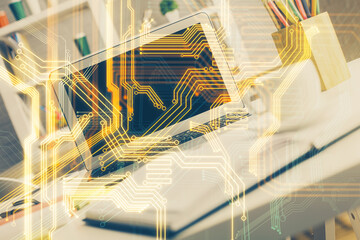 Computer on desktop in office with technology theme hologram. Double exposure. Tech concept.