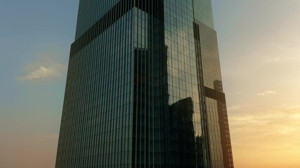 Aerial rising shot of a generic business skyscraper reflecting morning sky. Success concept