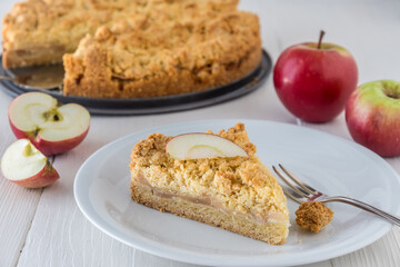 Slice of apple pie with sprinkles on white wooden table