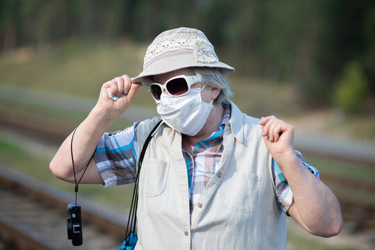 portrait of senior old woman with medical mask on face, hat,sunglasses and photo camera