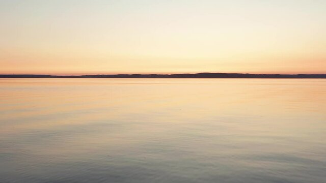 Done flight close over lake water surface at sunset. Beautiful colors right after sun went down. Nature finest art. calm windless night in orange yellow pink and purple. Background wallpaper aerial