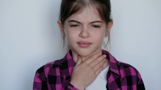 little / young girl holding a sore throat. Angina, tonsillitis, pharyngitis, a cold in a child.