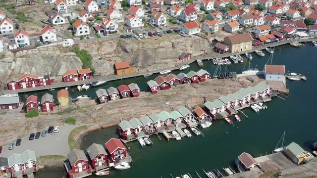 Fishing cottage or red boat hus cabins at the ocean on small rocky granite island. Villages or town of wooden houses in Sweden. Aerial drone flight over buildings. Anchoring boats in calm ocean waters