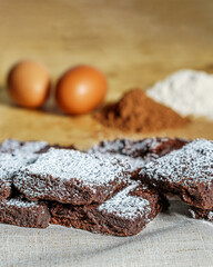 Vertical shot of brownie pieces covered in powdered sugar on a wooden surface