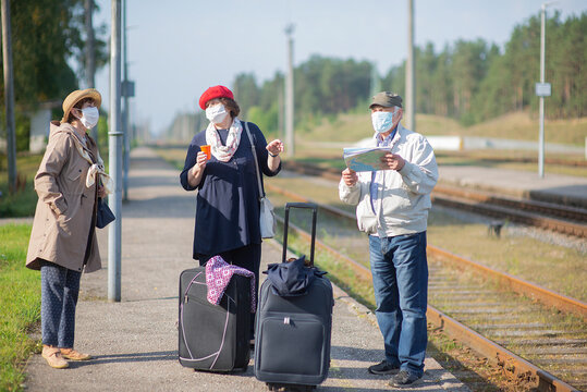 positive elderly seniors people with face masks waiting for train before traveling during a COVID-19 pandemic