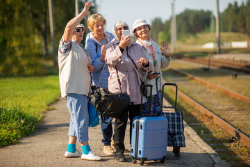 Group of senior women take a self-portrait on a platform waiting for a train to travel during a COVID-19 pand © Zelma