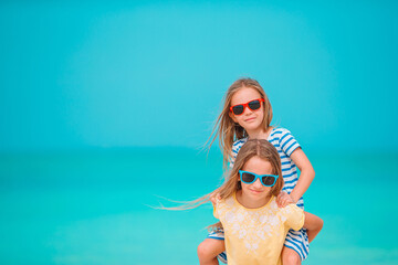 Fototapeta na wymiar Two little happy girls have a lot of fun at tropical beach playing together