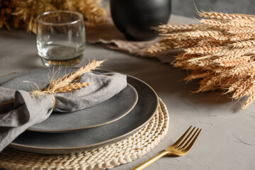 Autumn table setting with dry yellow oak leaves, fall decoration on grey. Thanksgiving day