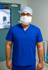 Fototapeta na wymiar Portrait of a doctor or medical specialist. Horizontal full size portrait. Man in scrubs. Operating room background.
