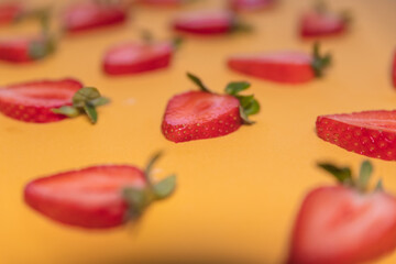 Selective focus shot of strawberry slices on an orange background