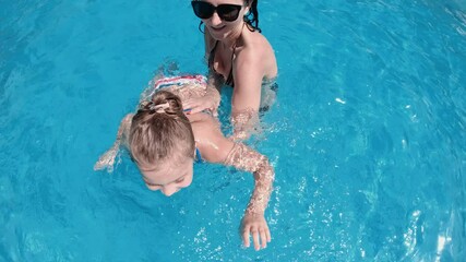 Family funny concept, beautiful woman training giving swimming lessons to her daughter in swimming pool