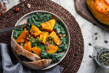 Top view of season salad with grilled pumpkin, kale, chickpea, pepitas and nuts. Autumn vegetarian healthy recipe.