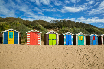 Rows of multi-coloured beach huts along Saunton Sands in North Devon, UK
