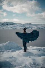 Woman in her twenties is enjoying nordic white winter while being cozy in her sweater, knitted hat...