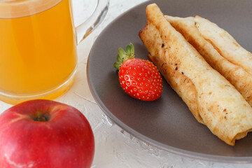 Homemade pancakes filled with cottage cheese on a plate and a cup of tea