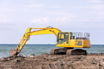 The excavator is working to build pier of harbor in the construction site. Excavators are heavy construction equipment consisting of a boom, dipper (or stick), bucket and cab on a rotating platform.