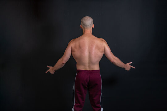 Pumped back at a bald young man on a black background