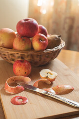 fall apple composition, wicker basket filled with red and yellow apples, peeled apple it front
