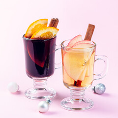 Red and white glogg or mulled wine with orange and apple slices and cinnamon stick, Christmas decoration pink background, square