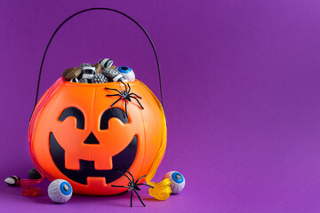 Jack-o-lantern bag full of liquorice candy on purple background with copy space,  horizontal