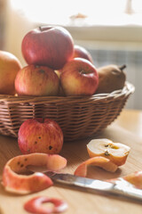fall apple composition, wicker basket filled with red and yellow apples, peeled apple it front
