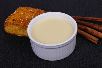 Condenced milk in the bowl with sinnamon and pastry