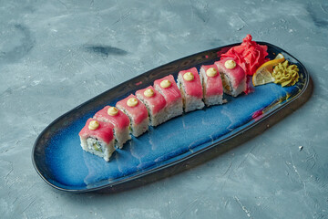 Sushi roll red dragon with tuna, cream cheese and avocado in a blue plate on a gray background. Japanese food