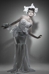 Obraz premium Young beautiful female model in a white dress on a white background with a shadow