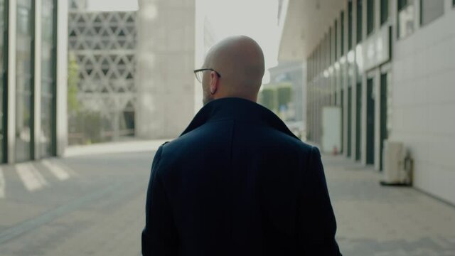 Back View of Businessman Walking Down the Street .