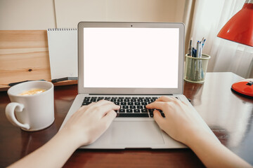 Front view of woman hands working on laptop with blank white screen standing on the wooden office desk.  mockup image blank screen computer with white background. 