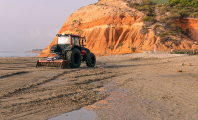 Tractor clean beach's sand after a storm