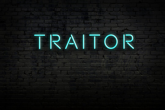 Neon sign. Word traitor against brick wall. Night view