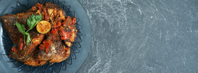 Homemade fried parrot fish with chilli is asian culinary food, served on a stone pad