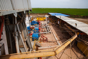 Panorama of oil deposit and equipment. of drill rig. Pipes and machines. Green field and blue sky...