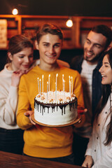young handsome man holding a cake which he gave his friends for his birthday. Birthday celebration with best friends