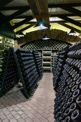 Wine cellar with wine bottles. Old wine bottles covered with dust and cobwebs are in the wine cellar of winery. Alcohol drink vintage storage