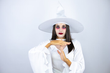 Woman wearing witch costume over isolated white background Doing time out gesture with hands,...