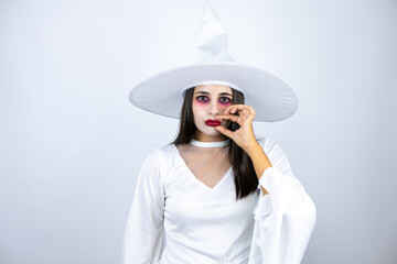 Woman wearing witch costume over isolated white background mouth and lips shut as zip with fingers....