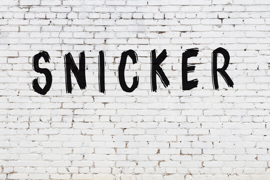 Inscription snicker painted on white brick wall