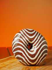 One zebra pattern doughnut on a wooden board and table, Warm orange sunny color background.