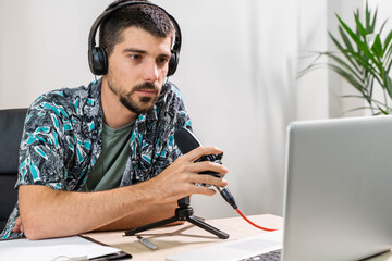 Man working as radio host at radio station sitting in front of microphone. Young radio host...