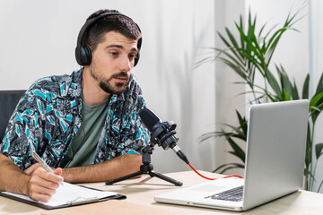 Man working as radio host at radio station sitting in front of microphone. Young radio host...