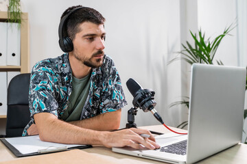 Man working as radio host at radio station sitting in front of microphone. Young radio host...