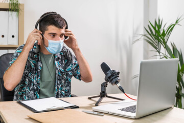 Man working as radio host at radio station sitting in front of microphone. Young radio host...