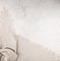 Pure washed linen cloth on light grunge stone background. Natural washed linen fabric on stone tile...