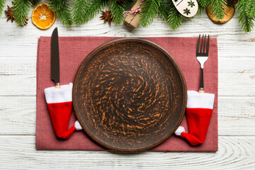 Top view of Christmas dinner on wooden background. Plate, utensil, fir tree and holiday decorations with copy space. New Year time concept