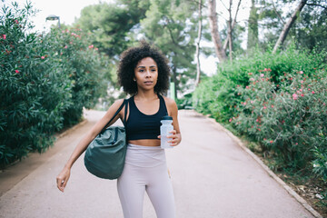 Confident African American woman with bottle of water in park